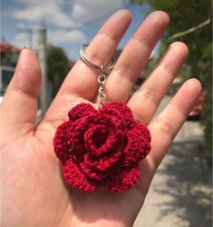 a crocheted rose keychain in the palm of someone's hand