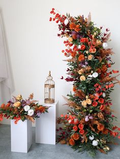 two white vases filled with flowers next to a birdcage