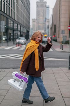 a woman is walking down the street with her cell phone in her hand and carrying a cooler