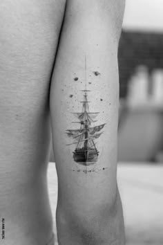 a black and white photo of a ship on the back of a man's leg