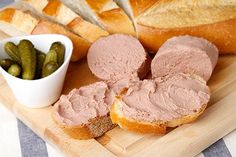 sliced meat and bread on a cutting board with pickles