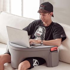 a young man sitting on a couch using a laptop computer