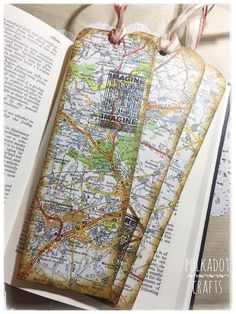 two bookmarks with maps on them are sitting next to an open book and some string