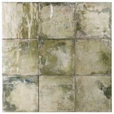 an old, dirty tile wall with green and white paint on the tiles in different colors