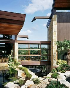 an outdoor area with rocks, plants and water features large windows that overlook the valley