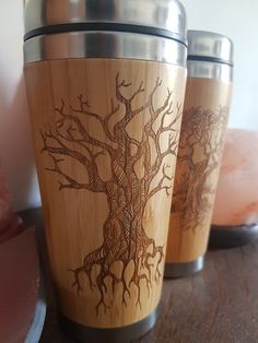 two wooden cups sitting on top of a table next to each other with trees engraved on them