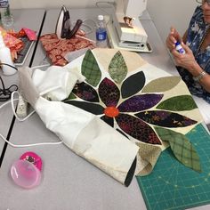 a woman sitting at a table working on a quilt