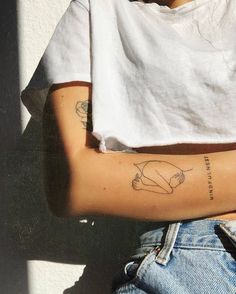 a woman's arm with tattoos on it and a white t - shirt behind her