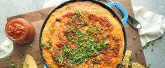 an omelet with tomatoes and herbs in a cast iron skillet next to tortilla chips