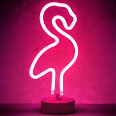 a neon pink flamingo lamp sitting on top of a table