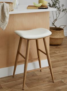 a white stool sitting in front of a counter top next to a potted plant