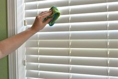 a woman is cleaning the window with a green mop and microfibre dust