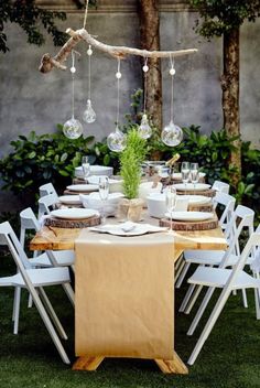 the table is set with white chairs and place settings for an outdoor dinner or party