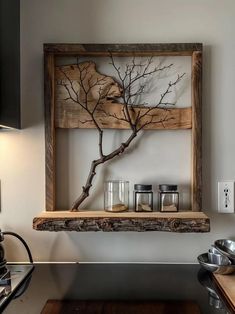 a wooden shelf with jars and spoons on it next to a wall mounted tree branch