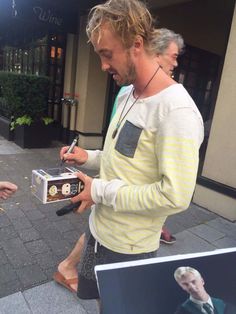 a man holding an old fashioned radio on the street while another person looks at it