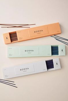 three incense sticks sitting next to each other on top of a white surface with the words boddha written in it