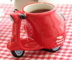 a red toy scooter coffee mug sitting on top of a checkered tablecloth