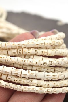 a hand is holding several white beads in it's palm, which are stacked together