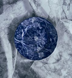 a blue and white plate sitting on top of a marble tablecloth covered in paper