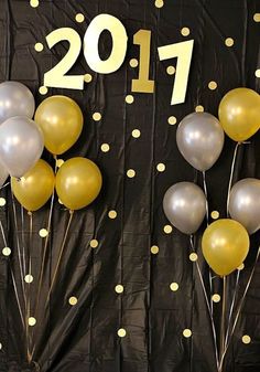 balloons and streamers are arranged in front of a black backdrop with gold polka dots