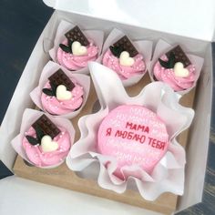 a box filled with pink cupcakes covered in frosting and topped with chocolate