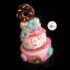 a three tiered cake decorated with donuts and sprinkles