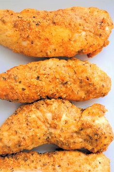 four pieces of chicken sitting next to each other on a white plate with seasoning