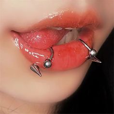 a woman's tongue with piercings on it and two balls attached to the lip