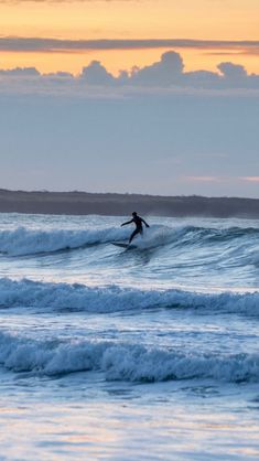 a person riding a wave on top of a surfboard in the ocean at sunset