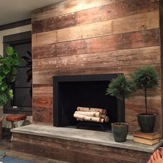 a living room filled with furniture and a fire place covered in wood planks next to a potted plant