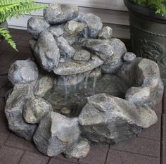 a water fountain surrounded by rocks and plants