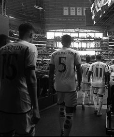 several soccer players are walking down the field in their uniforms and numbers on their shirts