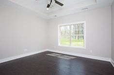 an empty room with hard wood floors and a ceiling fan in the middle of it