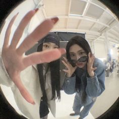 two women taking a selfie in front of a mirror with one hand up to the camera