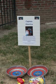 there is a sign that says captain america next to two metal bowls with arrows on them