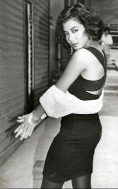 an old photo of a woman leaning against a wall with her hand on the door