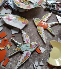 broken plates and bowls are sitting on the floor with broken glass shards all over them