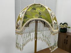 an umbrella with beaded fringes hanging from it's side in front of a window