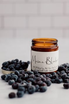 a jar of blueberries sitting on top of a table next to some blackberries