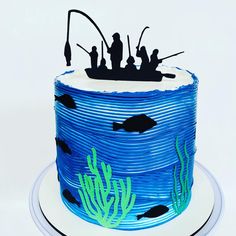 there is a blue cake decorated with people on a boat in the water and corals