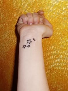 a woman's arm with three stars tattooed on the left side of her wrist