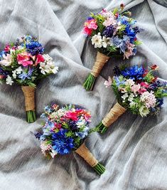 three bouquets of flowers are laid out on a bed sheet with the same color