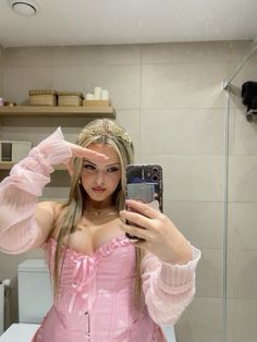 a woman in a pink dress taking a selfie with her cell phone while wearing a tiara