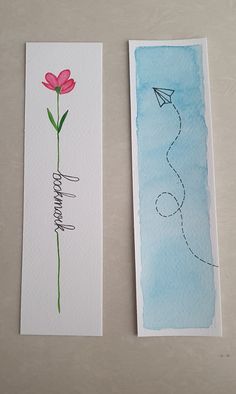 two cards with watercolors on them, one has a flower and the other has a paper airplane