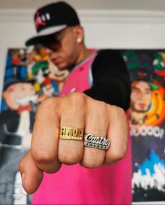 a man in a pink shirt and black hat pointing his finger at the camera