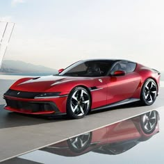 a red sports car parked on the side of a road next to a body of water