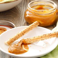 peanut butter and jelly sandwich on a white plate with two jars of jam in the background