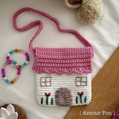 a crocheted purse sitting on top of a bed next to a teddy bear