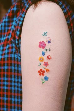 a woman's arm with flowers painted on the back of her left arm and shoulder