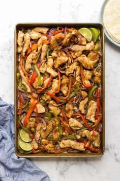 chicken fajita casserole in a pan with limes and red peppers